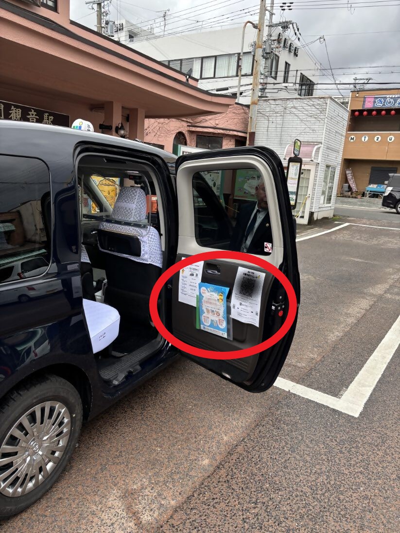 デマンド交通車両の写真(扉内に二次元コードとチラシを設置している様子を写しています。)