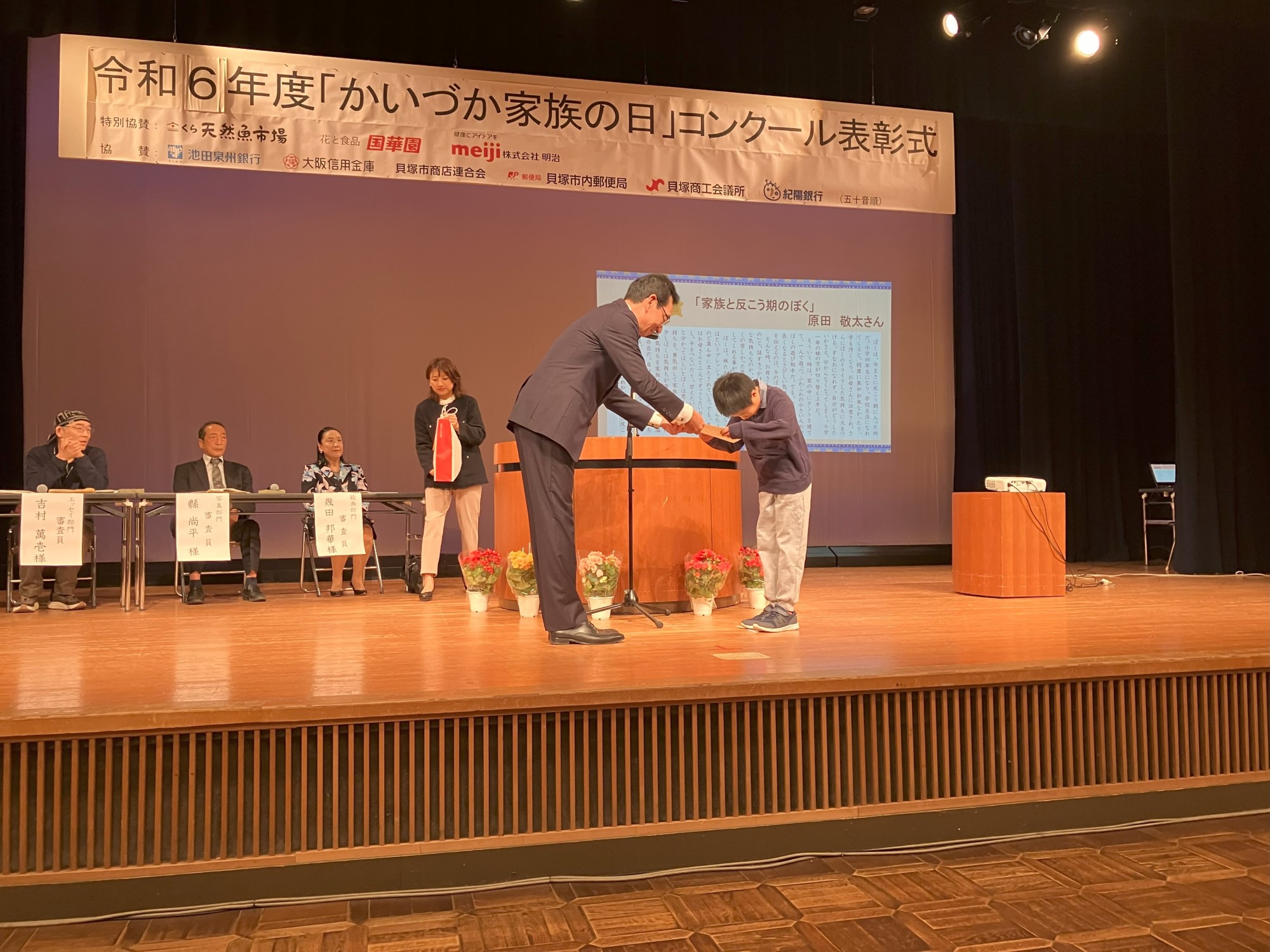 エッセイ部門表彰  最優秀賞受賞者が壇上で賞状を受け取る様子