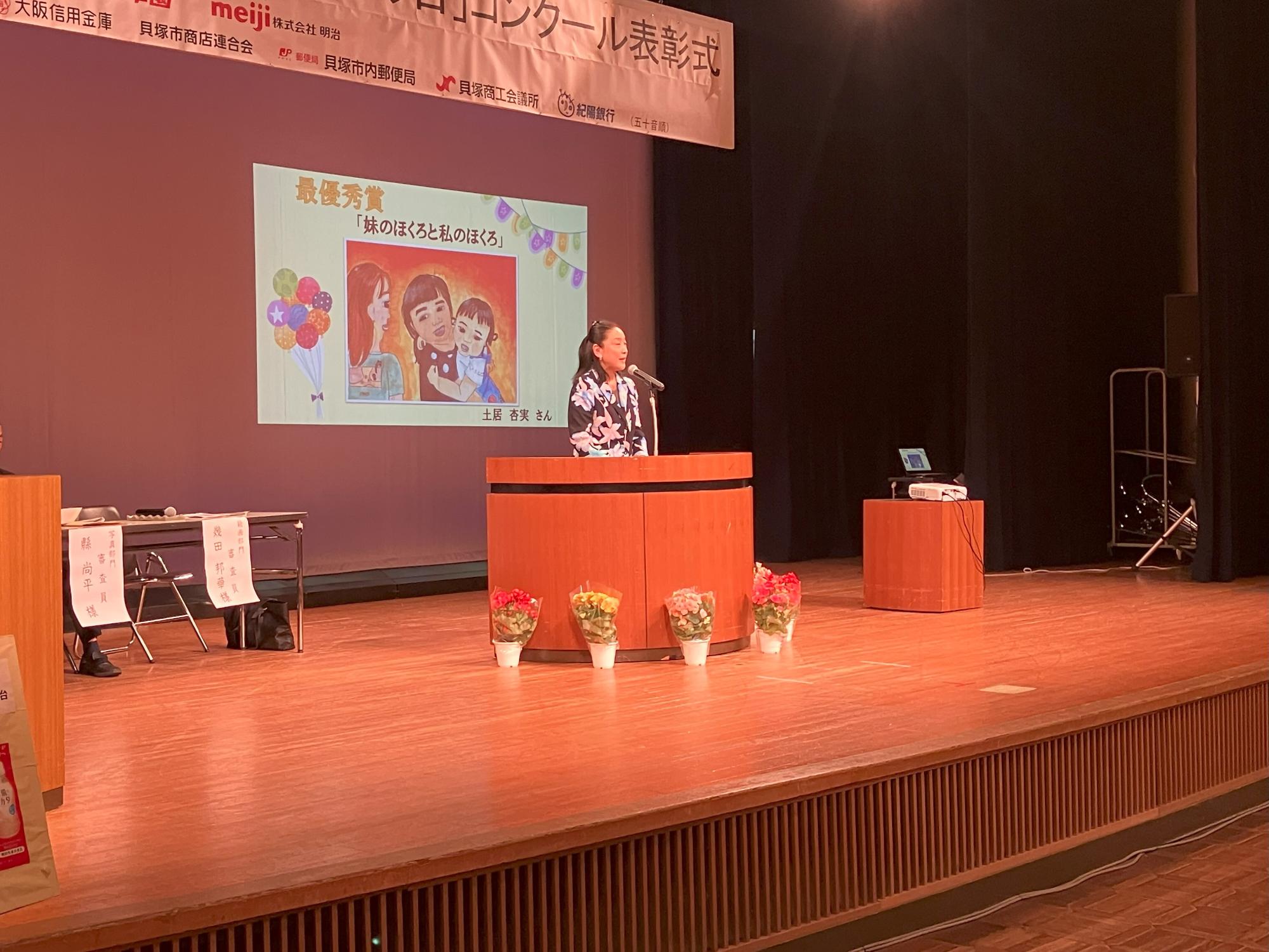 絵画部門講評の様子について舞台上のスクリーンに「最優秀賞」のスライドが映し出されている