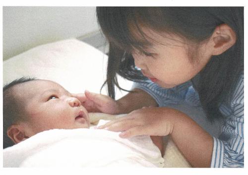 令和5年度かいづか家族の日の写真部門優秀賞作品です 生まれたての赤ちゃんと姉が見つめ合っている写真です