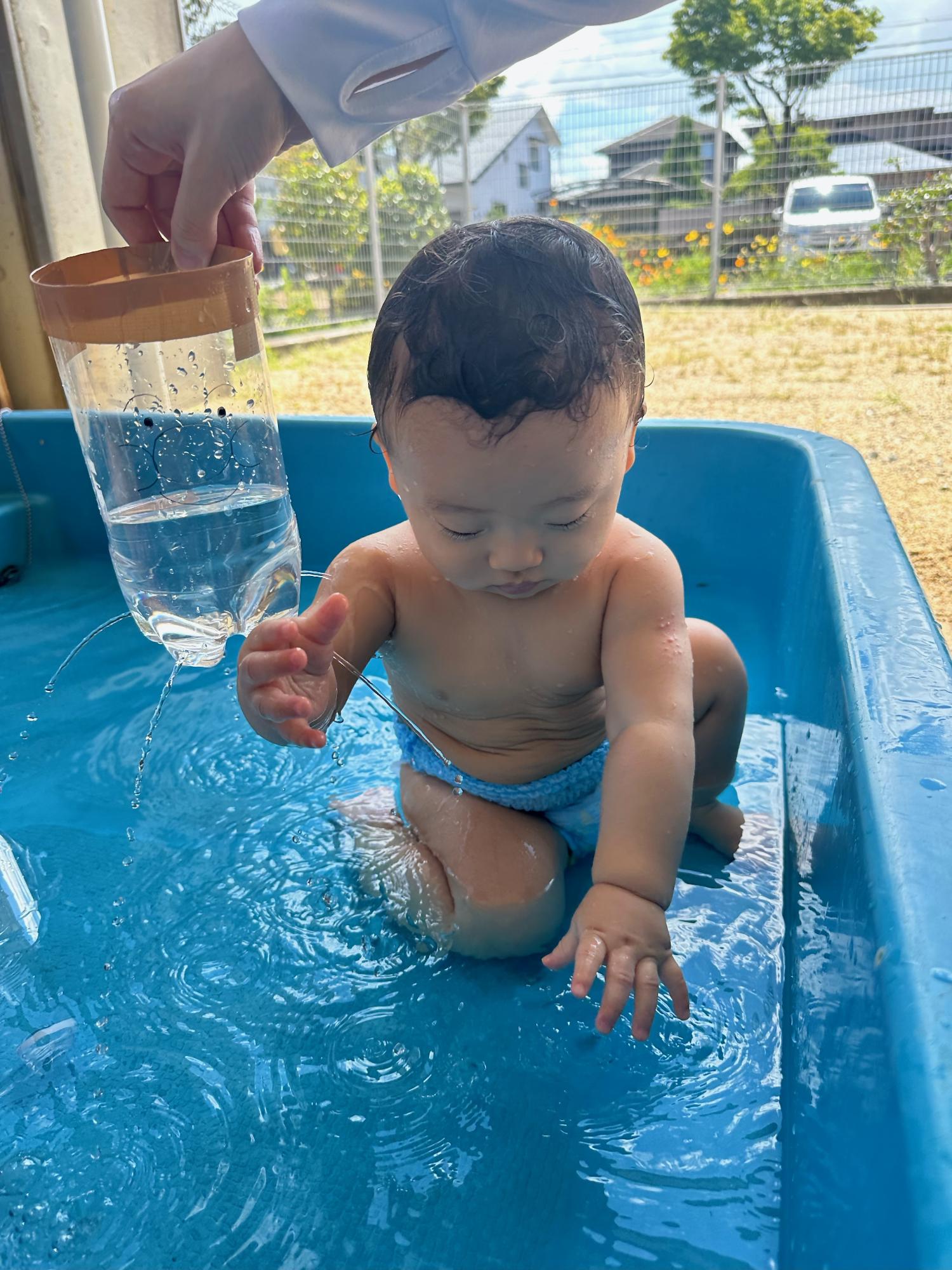 赤ちゃんが水遊びをしている様子