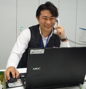 職場の自席で電話対応をする職員の様子です。