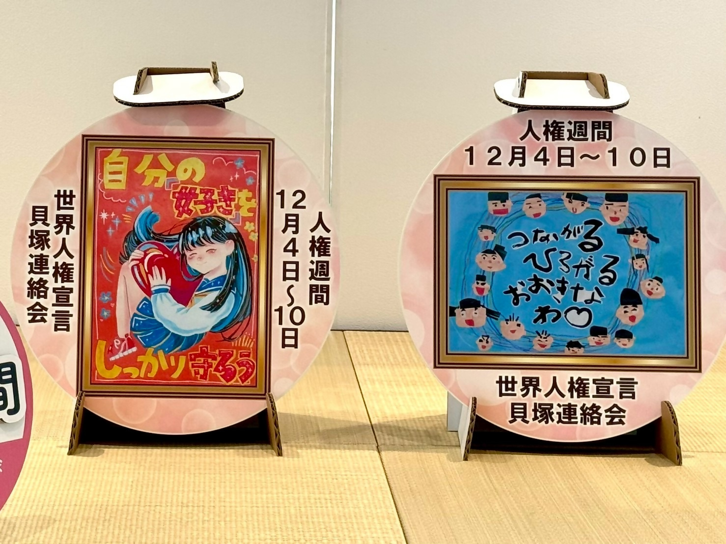 昨年度エントランスホールに展示したヘッドマークです。1枚は南幼稚園5歳児こあら組の園児の共同作品です。5歳児こあら組の子どもたち一人ひとりが描いた自分の顔は、個性豊かで、それぞれの輝きや特徴が表れています。もう1枚は第5中学校3年生の生徒作品となっており、自分の好きを守ろうと書かれた女の子が描かれています。