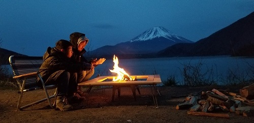 令和元年度かいづか家族の日の写真部門最優秀賞作品です 冬の富士山を背景に湖畔でキャンプをしている父子が焚火で暖を取っている様子を写した写真です