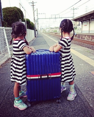 令和元年度かいづか家族の日の写真部門優秀賞作品です 水間線貝塚駅のホームで 同じボーダーのワンピースを着た女の子二人が大きなキャリーケースの両側に立って線路を見ている姿を後ろから写した写真です