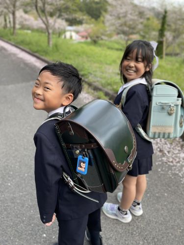 小学1年生になった男の子が新しいランドセルを背負い、3年生の姉と一緒に笑顔で写っている写真です。