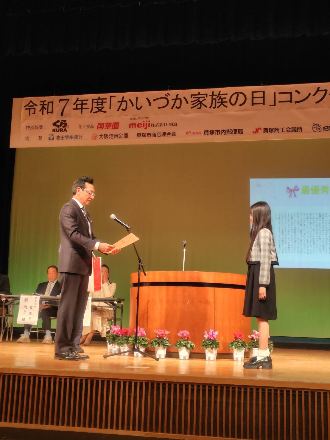 教育長がエッセイ部門の最優秀賞受賞者に表彰状を授与している様子です。