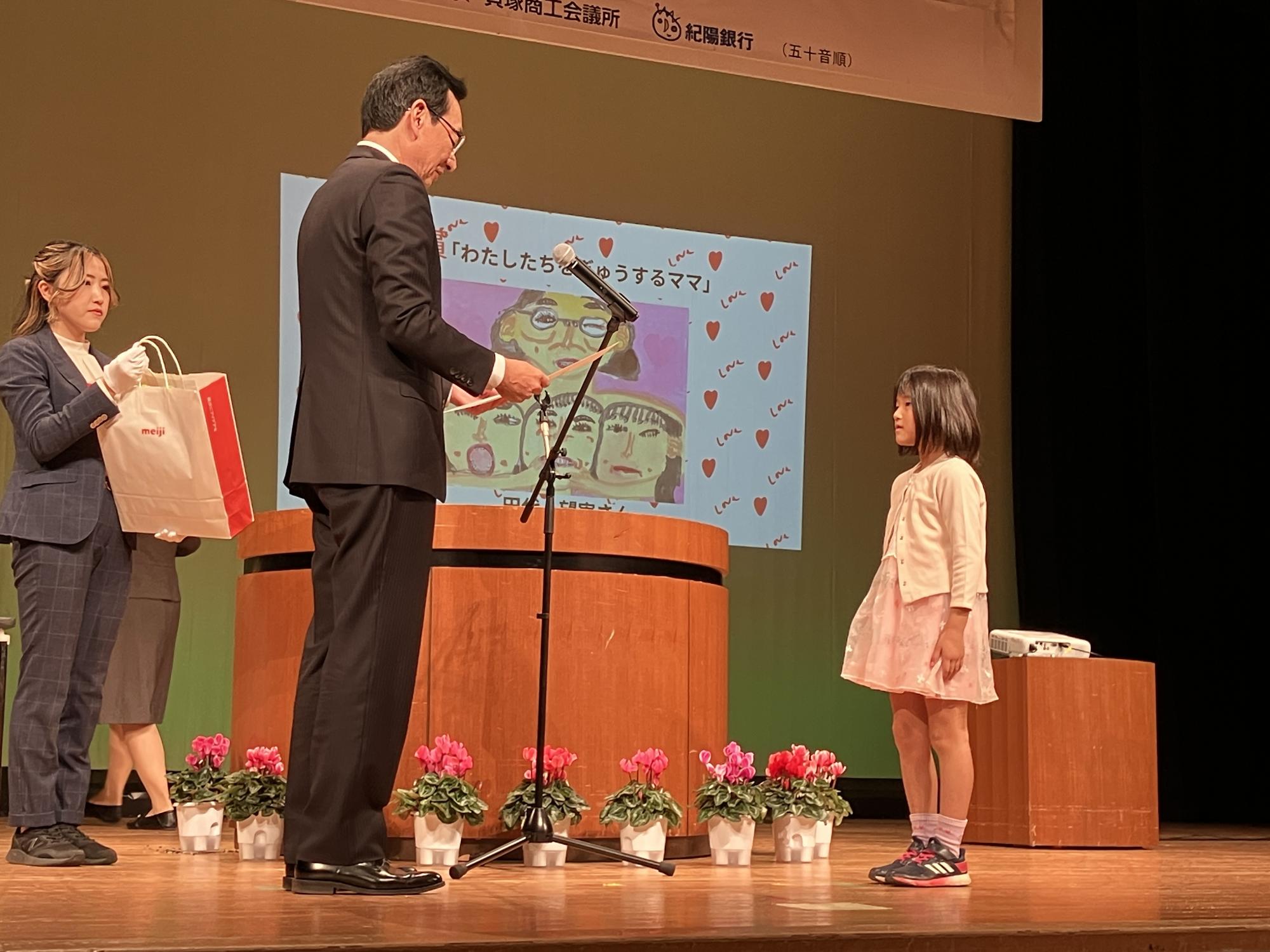 教育長が絵画部門の最優秀賞受賞者に表彰状を授与している様子です。