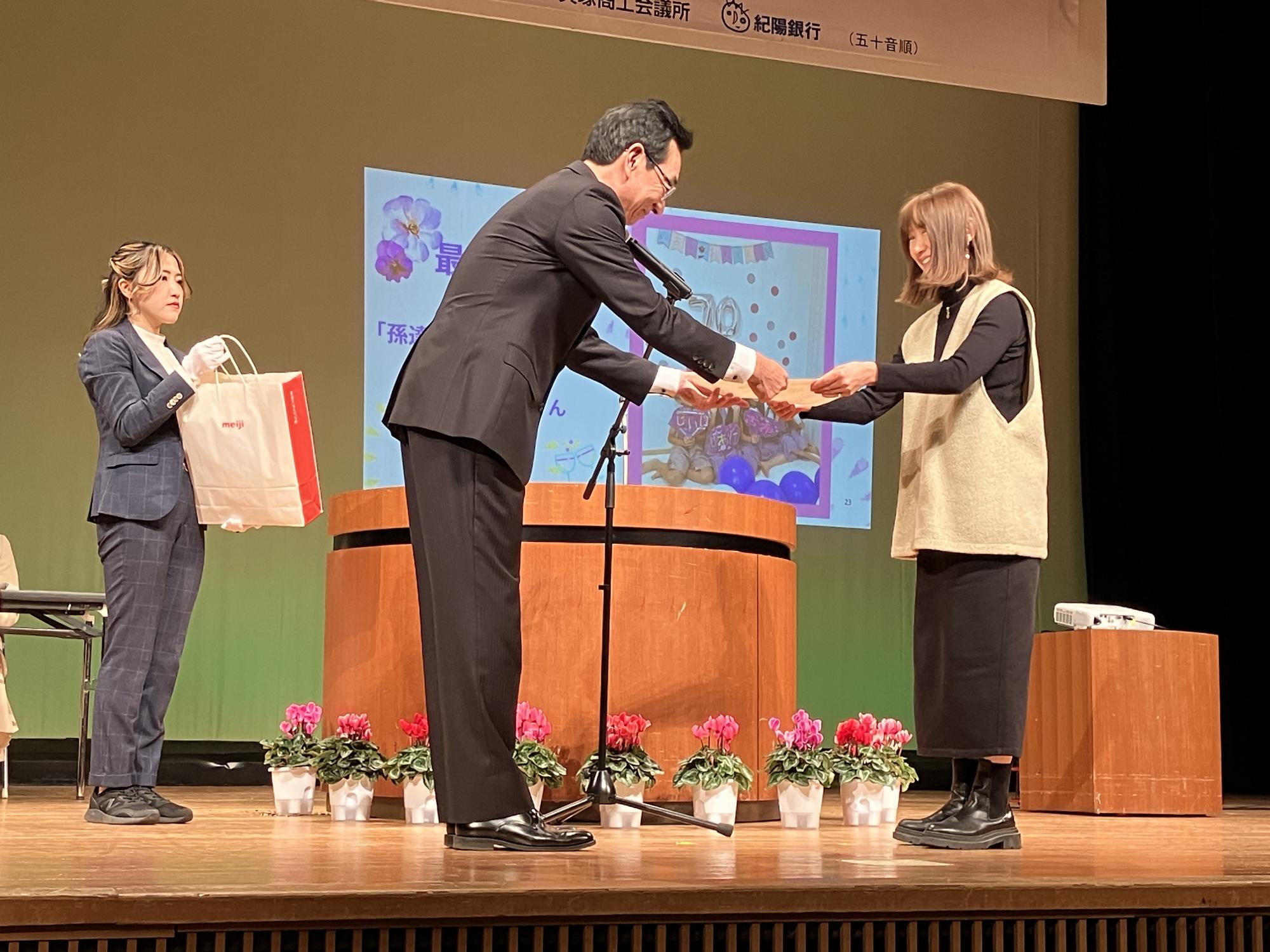 教育長が写真部門の最優秀賞受賞者に表彰状を授与している様子です。