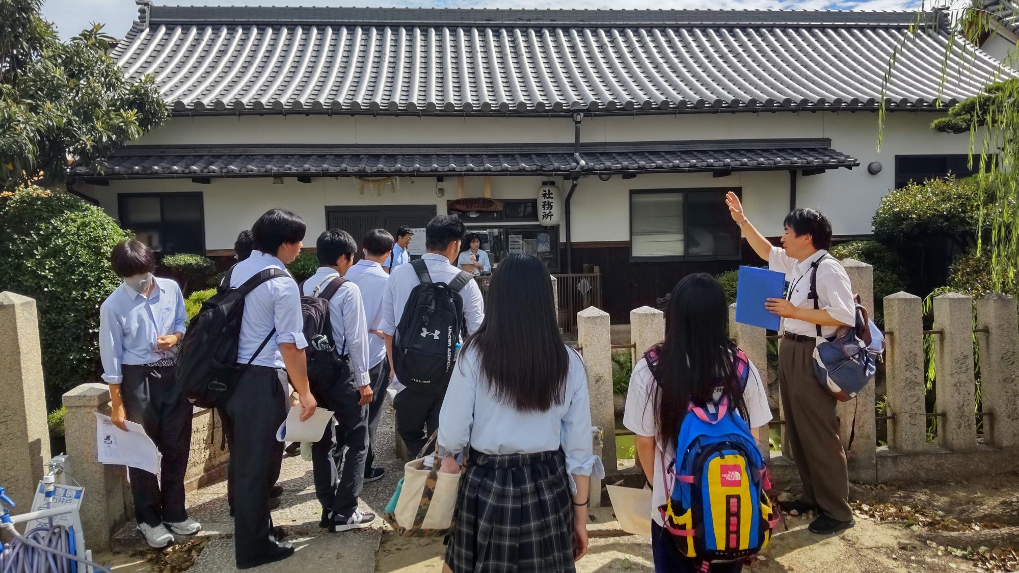 感田神社境内に遺された寺内町の濠をのぞき込む高校生