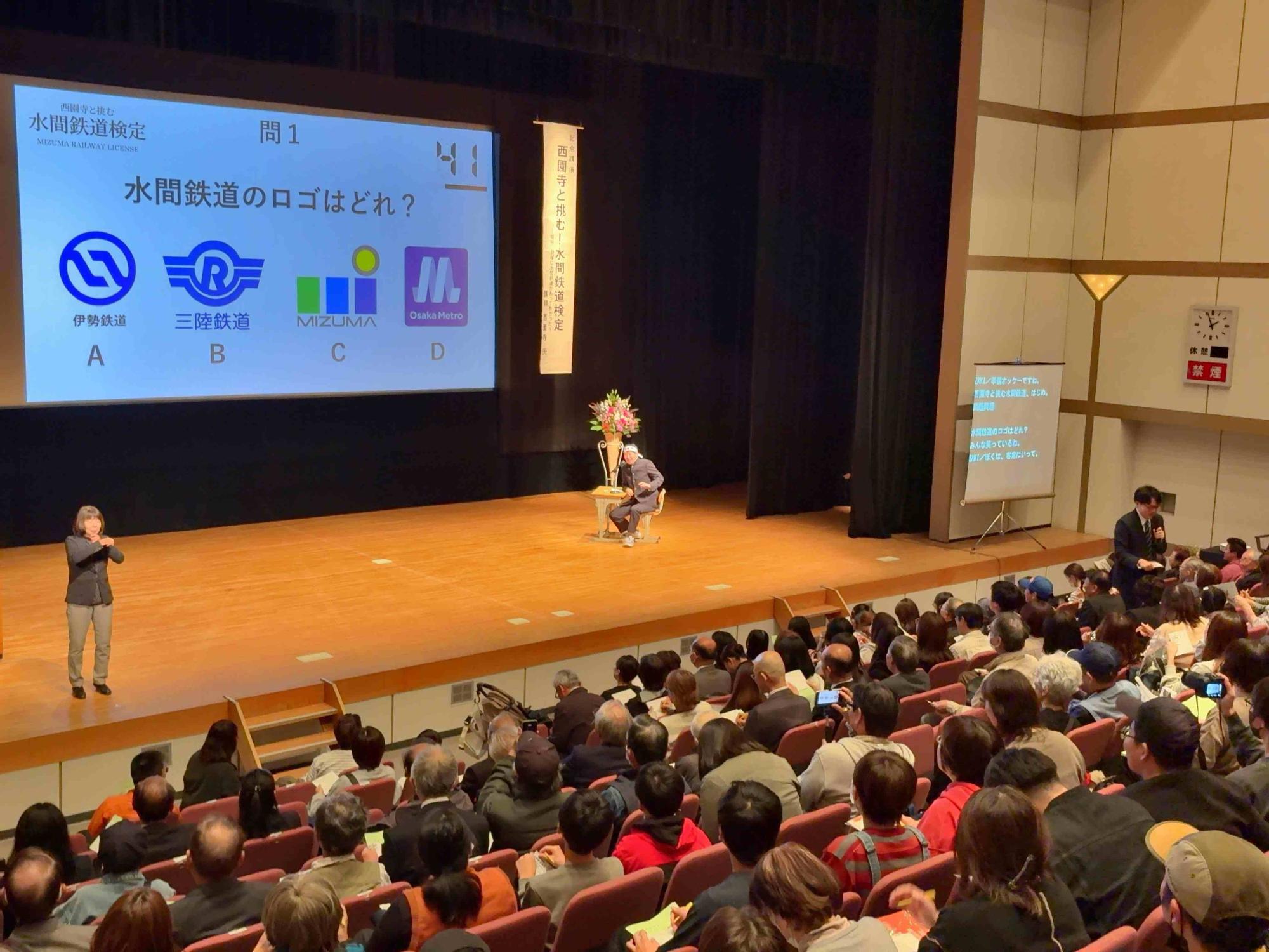 文化の日のつどい 講演会（壇上に登壇者とスクリーン）