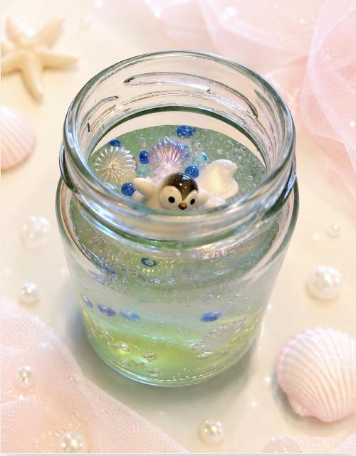 保冷剤で作成したアロマボトルの見本写真です。透明の瓶の中に保冷剤が詰められており、その中にビーズや貝殻、ペンギンのフィギュアが入っています。