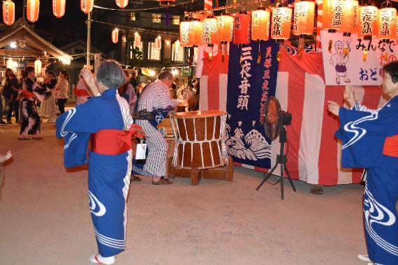 浴衣を着た女性たちが櫓の周りで貝塚三夜音頭を踊っている写真