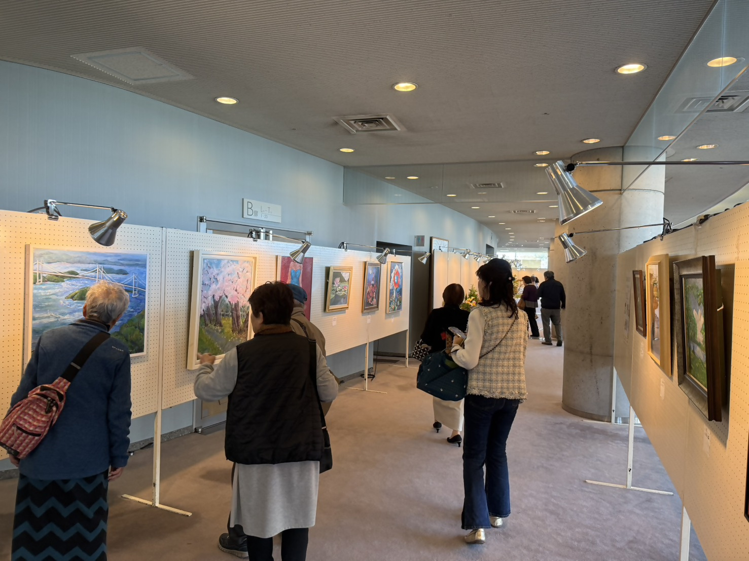 大ホールに展示された絵画作品を市民のかたが見ている様子