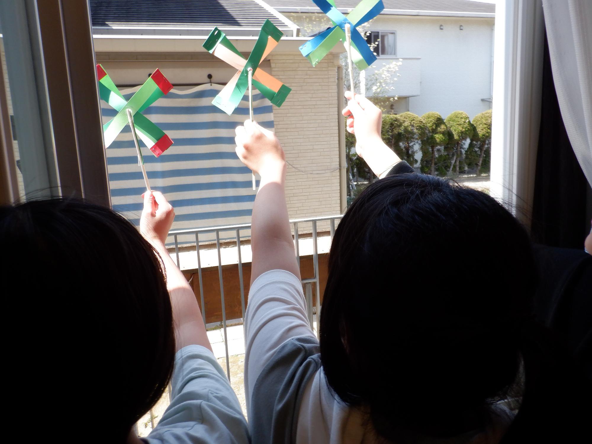 自分で作った風車を風に当てて遊んでいる様子