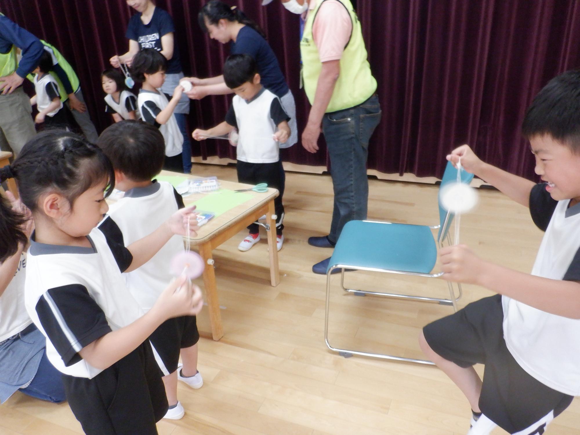 子どもたちが自分で作ったブンブンゴマで遊んでいる様子