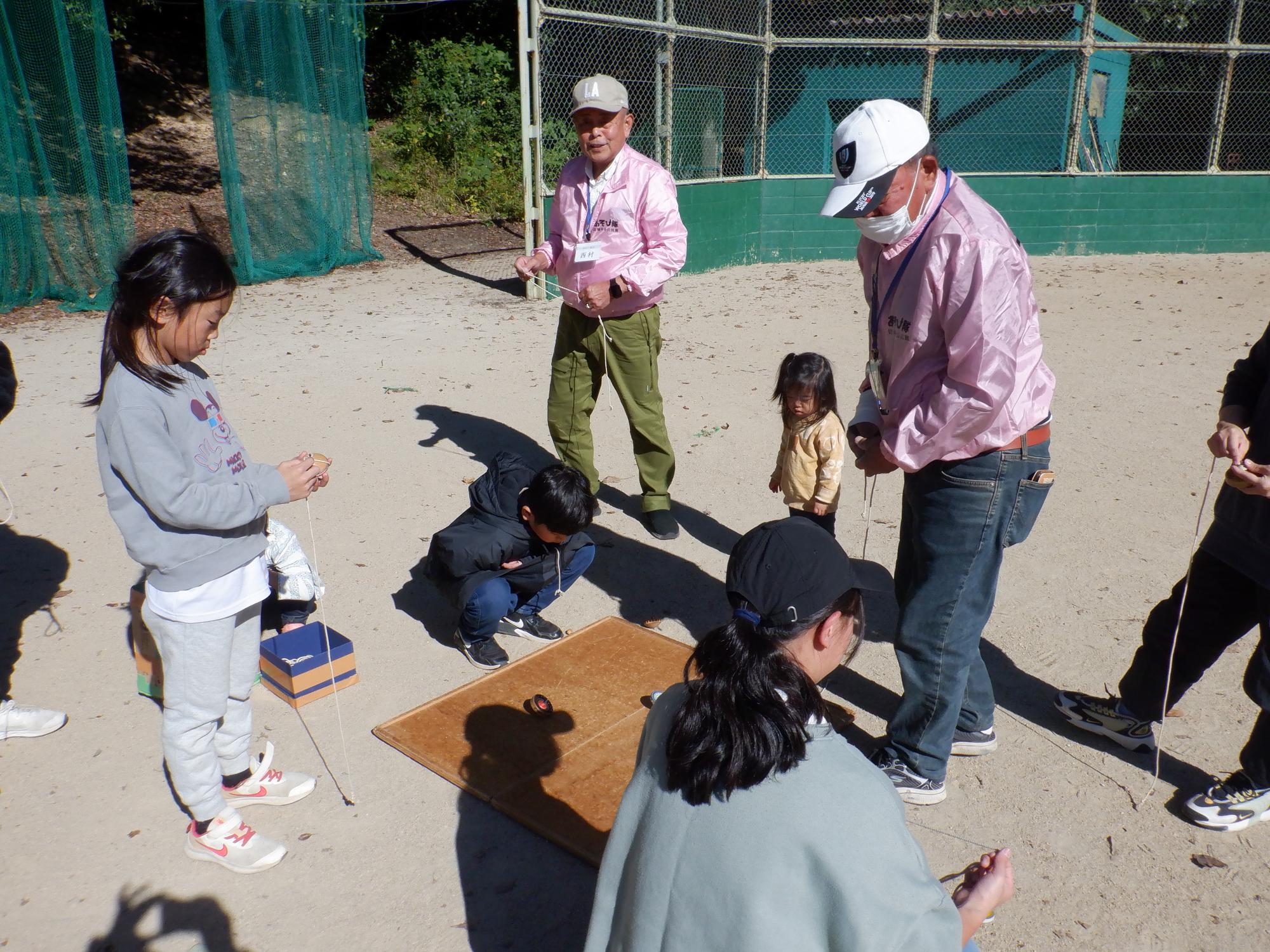 子どもたちがコマ回しで遊んでいる様子