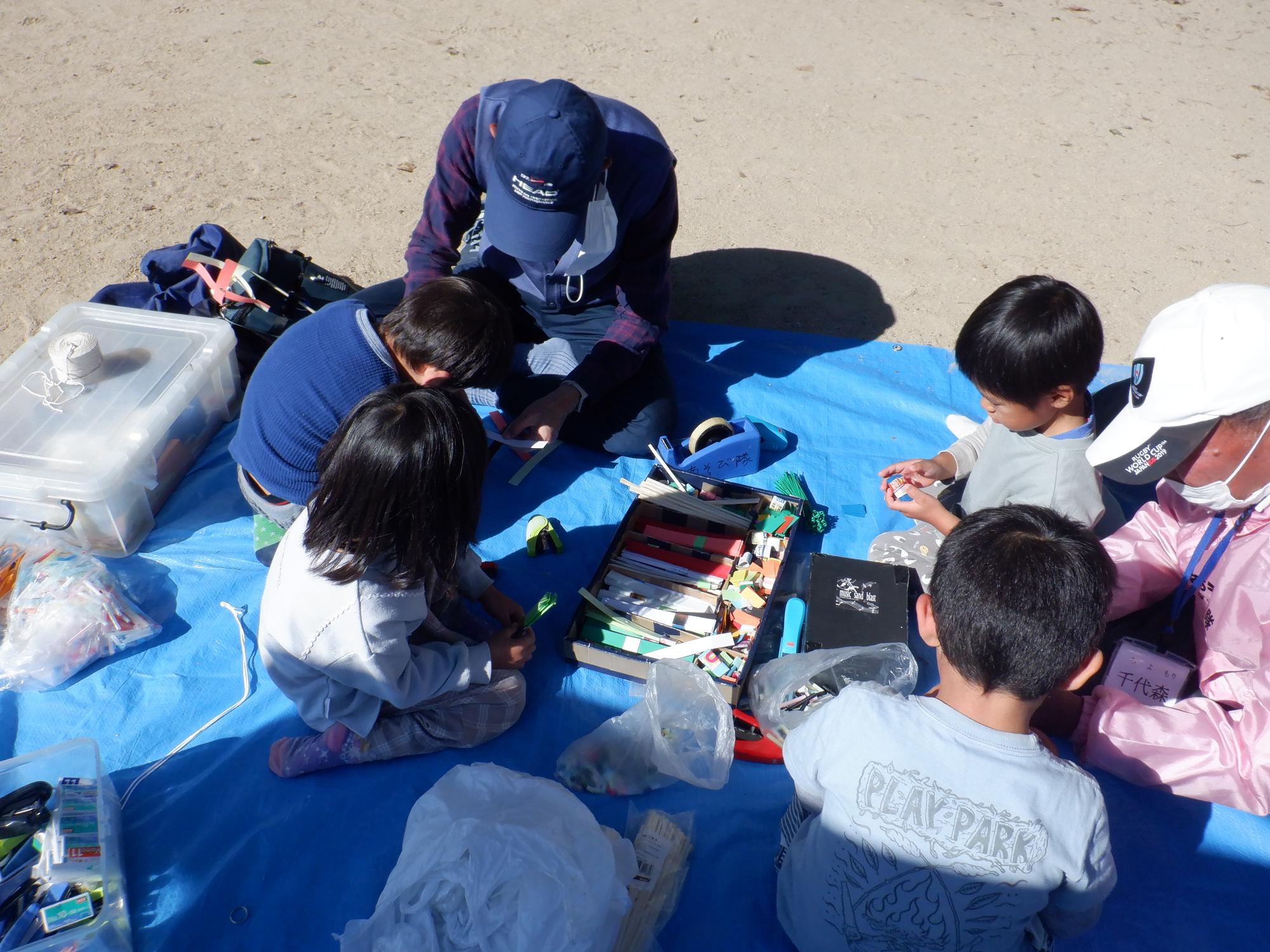 あそび隊に教えてもらいながら、子どもたちが風車を作っている様子