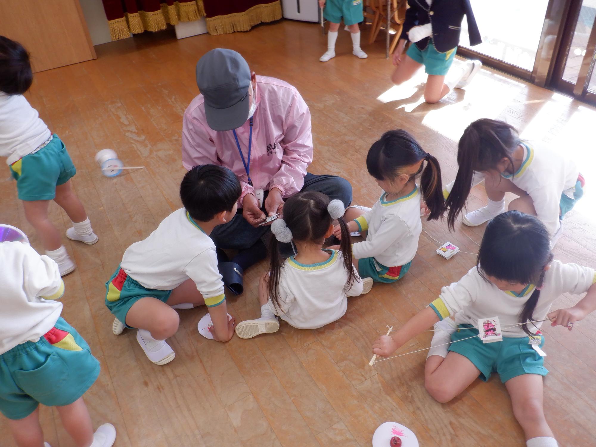 隊員が子どもたちにおもちゃの作り方を説明している様子