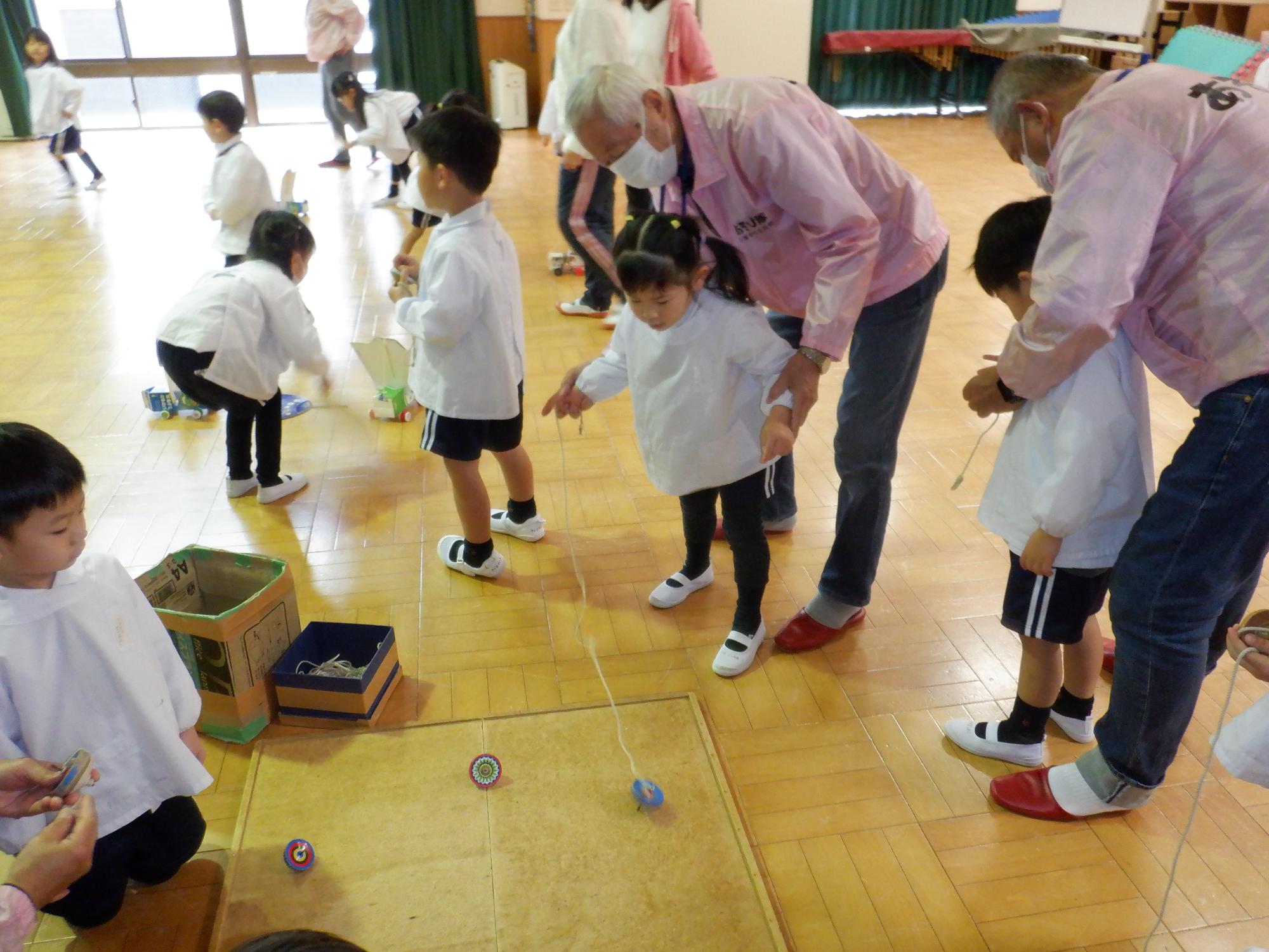 隊員と子どもが一緒にコマを回している様子