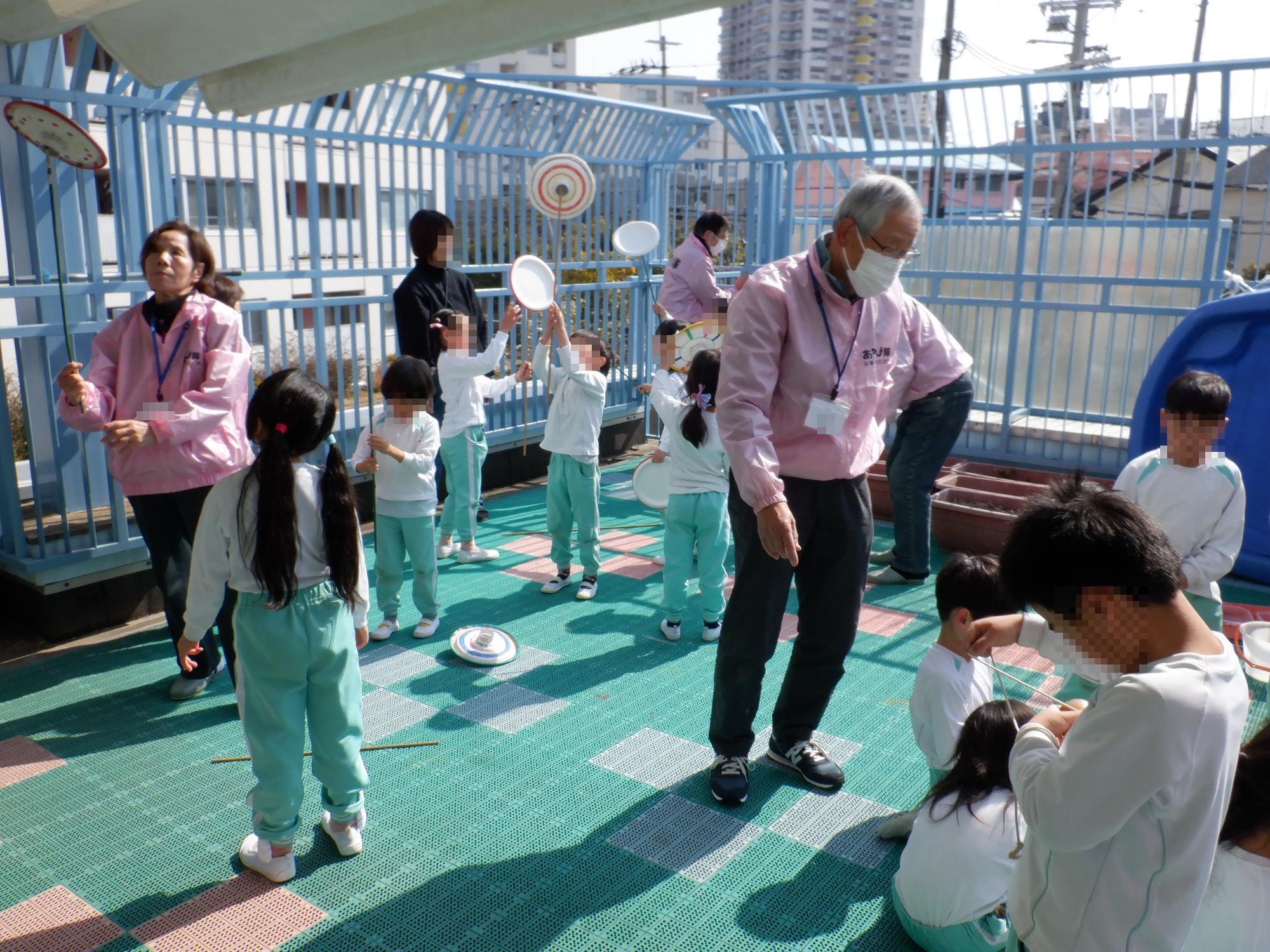 こどもたちが隊員と一緒に皿回しで遊んでいる様子
