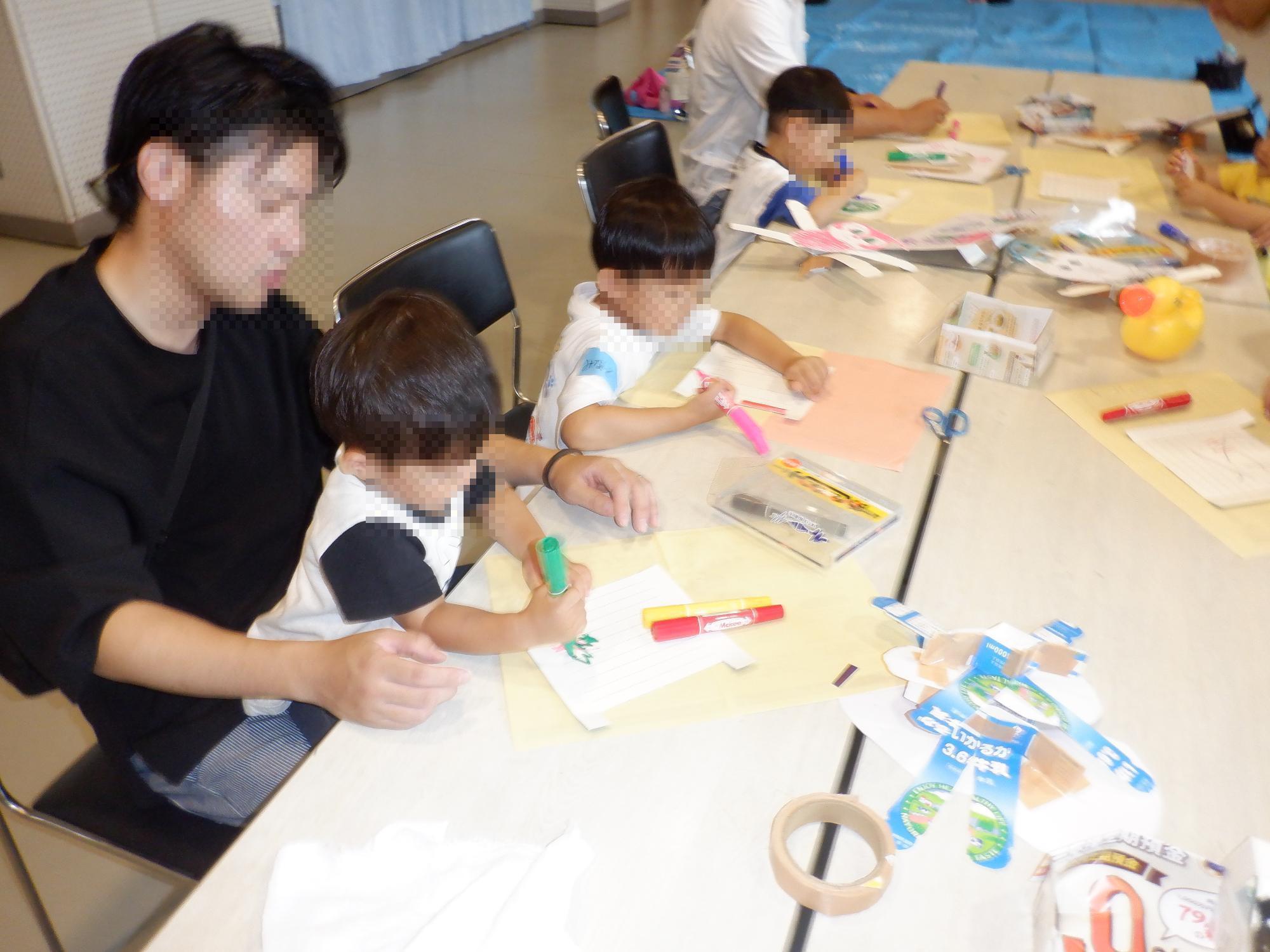 お父さんと子どもが手作りおもちゃに色をぬっている様子