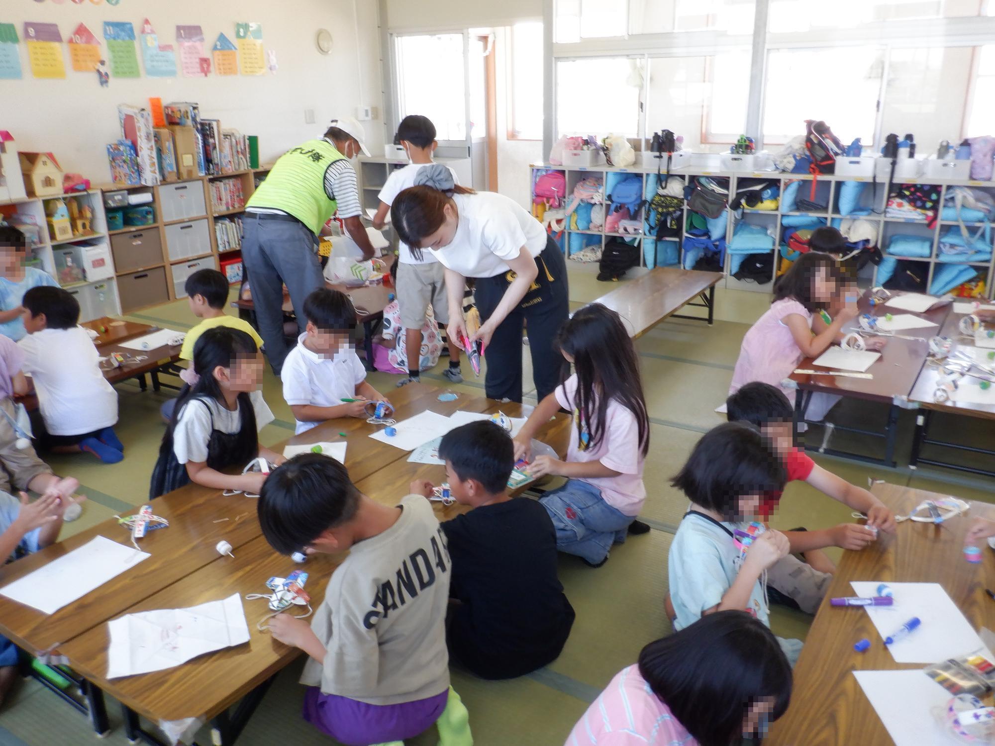 子ども達がブンブンゴマを工作している様子です