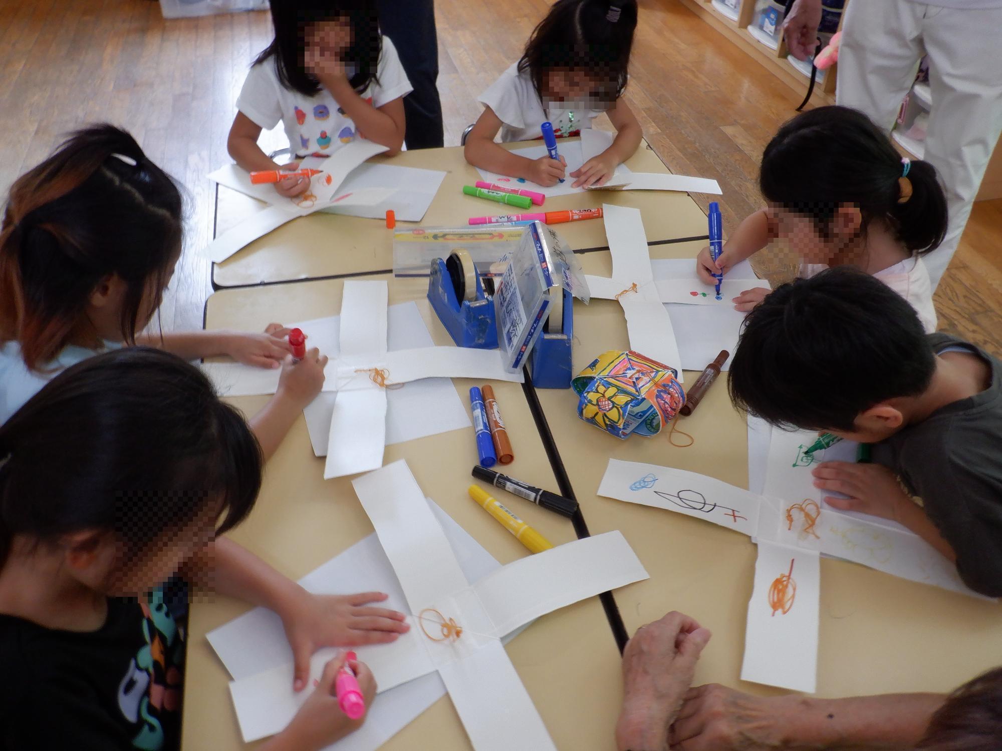 子ども達が牛乳パックヨーヨーにマジックで絵を描いている様子です