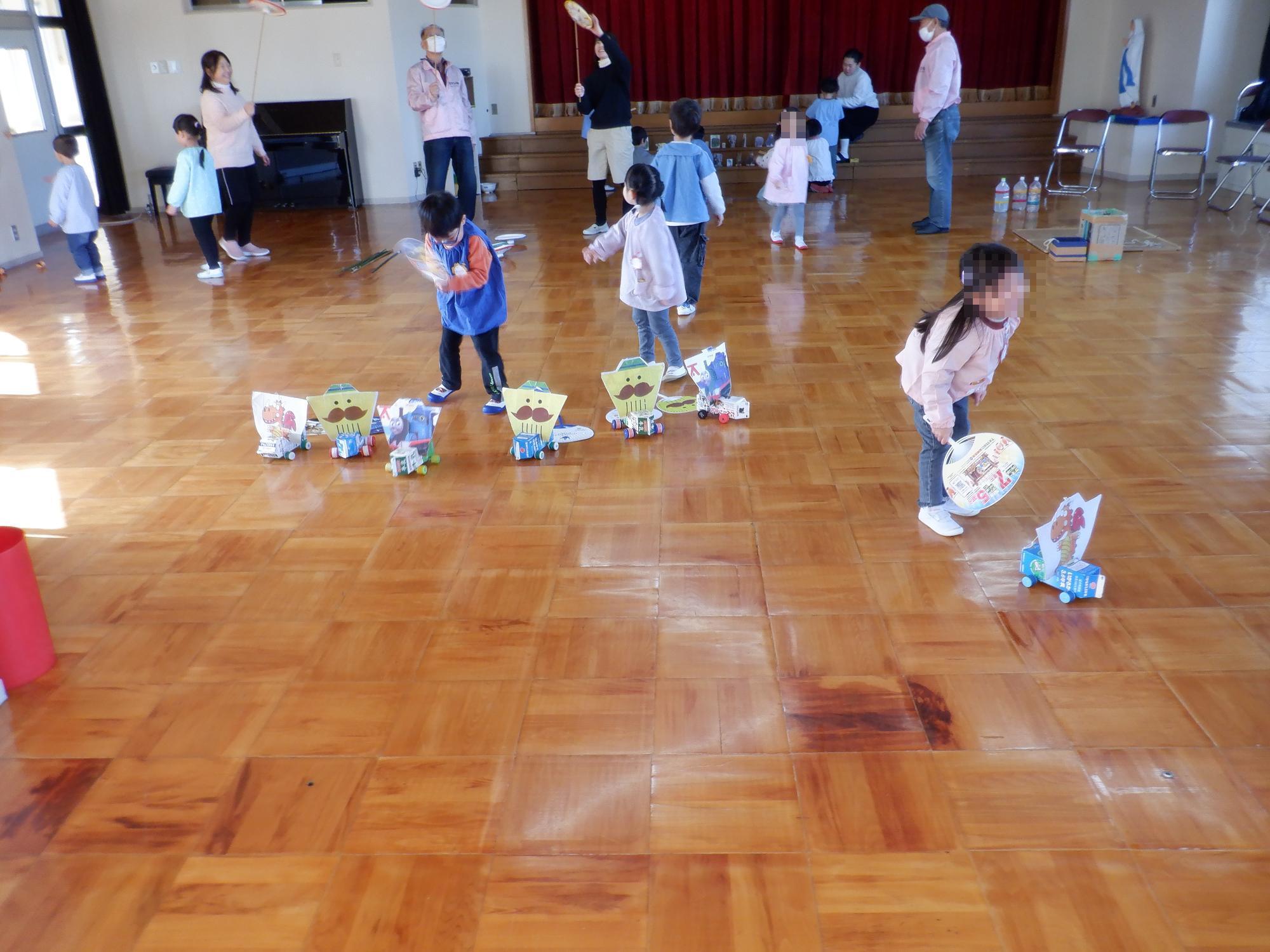 子ども達が牛乳パック自動車で遊んでいる様子です