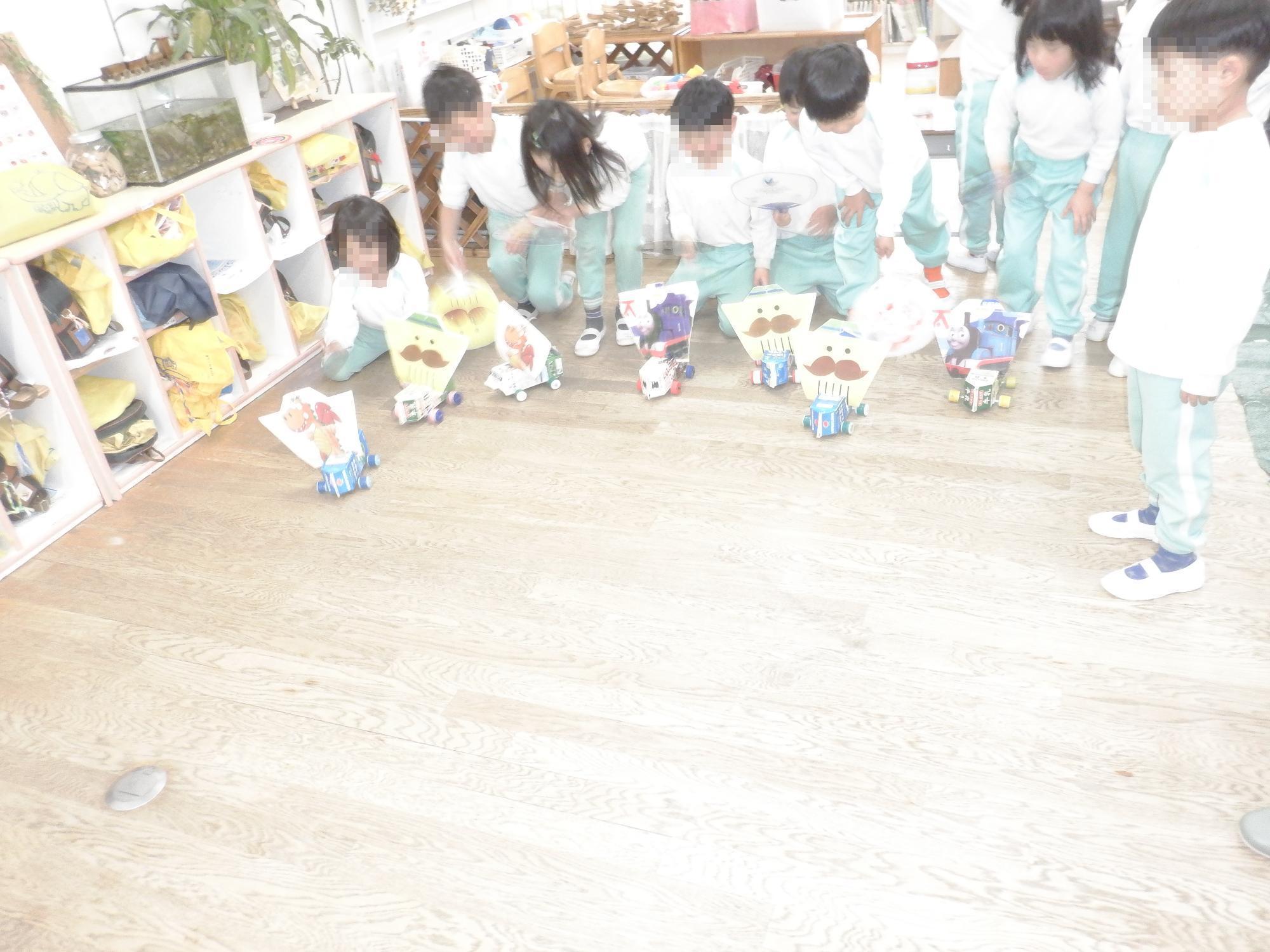 子ども達が牛乳パック自動車で遊んでいる様子です