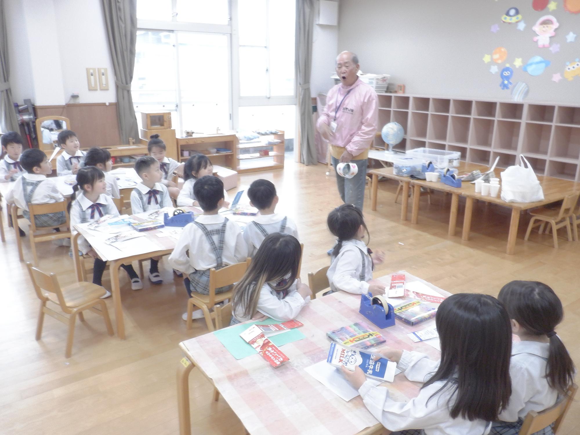 子ども達が牛乳パックヨーヨーの作り方の説明を聞いている様子です