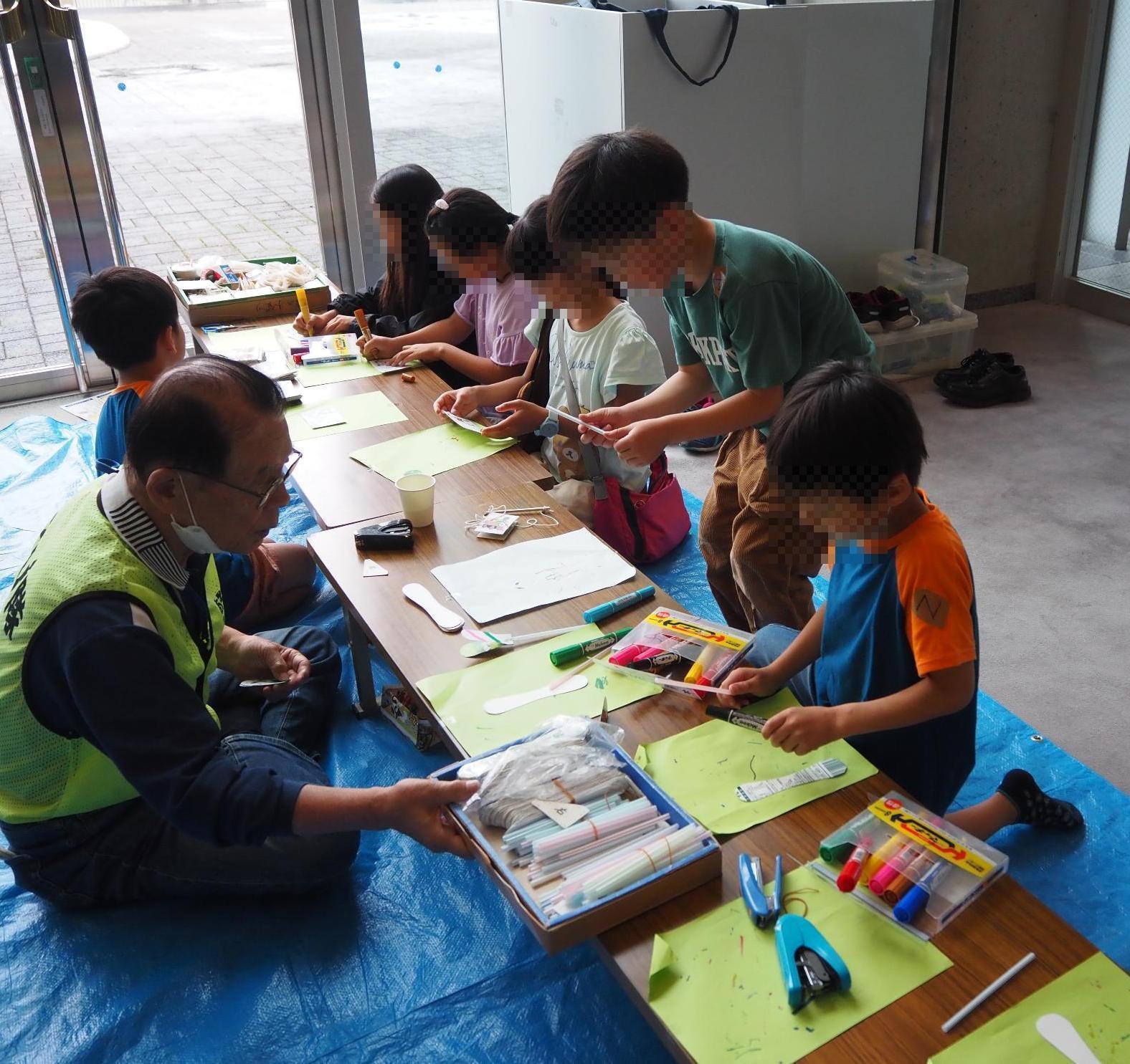隊員が子どもたちにおもちゃの作り方を説明している様子