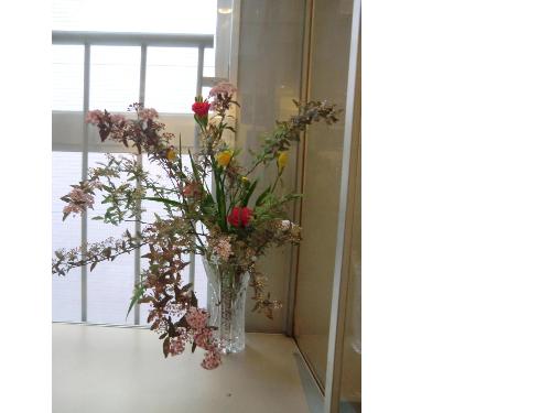 はなを楽しむ（ピンクや赤、白の花とともに立派な葉っぱも花瓶に入れて飾られている）