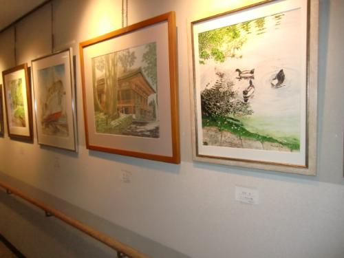 貝塚美術協会の作品展（自然の中の風景が描かれた絵画が、額縁に入れて廊下の壁に掛けて飾られている）