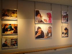 日本語パネル展（学習者が支援者と向かい合って読み書きを学び、会話をする様子の写真が飾られている）