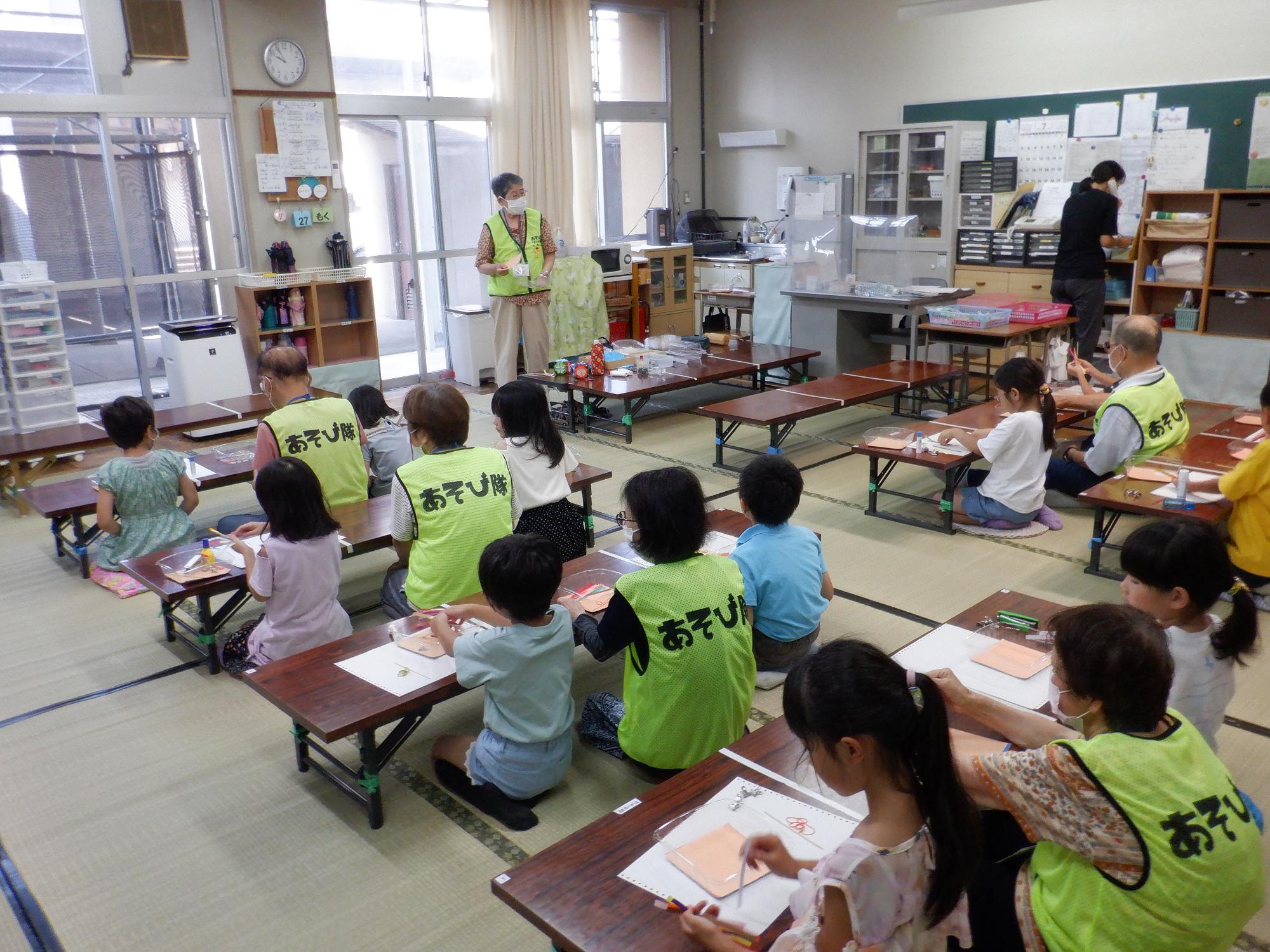 隊員が子どもたちにおもちゃの作り方を説明している様子