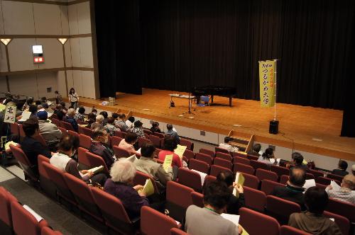 つるかめ大学昨年度の開講式の様子です  舞台上には「つるかめ大学」の文字が書かれたのぼり旗が設置されています