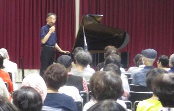 宮崎剛さんがピアノの前に立って客席に語りかけています。