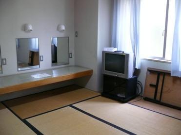 楽屋（和室）の写真（壁掛けの鏡が二つと、鏡の前には壁掛けテーブルがある  テレビ、背の低い長机が置かれている）