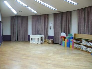 保育室の写真（ベビーベッド、本がたくさん収納された本棚、その他おもちゃが置かれている）