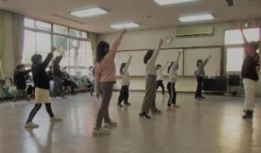キッズダンス講座の様子の写真です。講師にならって受講生たちが右手を上げてポーズを取っています。