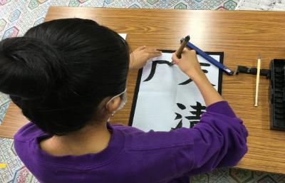 子どもが毛筆講座で漢字の月という字を書いている様子