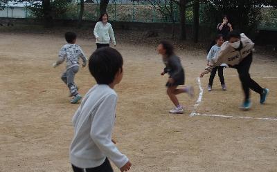 子どもと大学生が一緒に鬼ごっこをしている様子