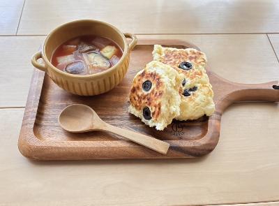 木製プレートにのせられたスプーンと、野菜たっぷりのミネストローネと豆腐フォカッチャ