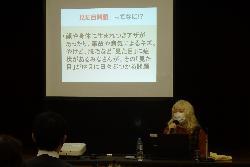 スクリーンの前で講演する藪本さん
