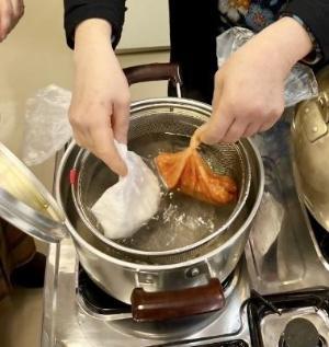 具材を入れたポリ袋を鍋で温めている様子
