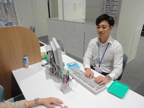 職員が窓口カウンターに座り市民の応対をしている様子です。