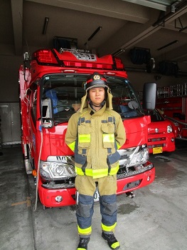 消防車の前で防火服を着た消防職員が立っている様子です。