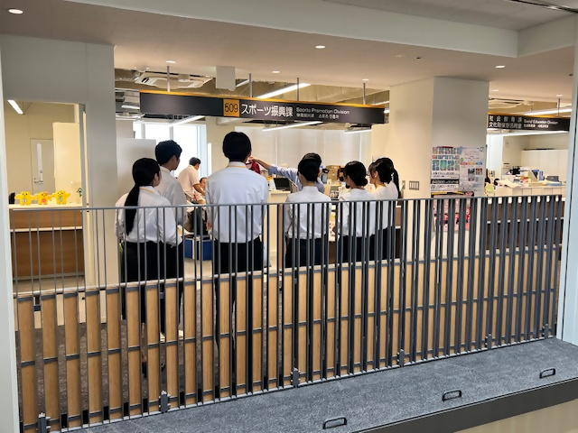 人事課職員が見学者にスポーツ振興課について説明している様子