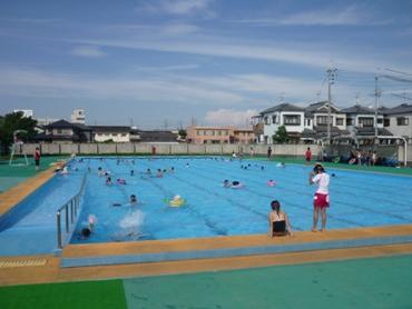 青空のした、市営のプールで泳ぐ子どもたち